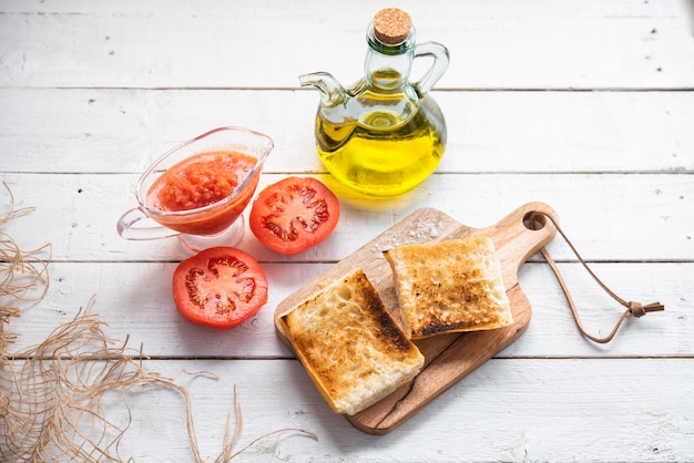 Pain grillé sur un bois avec une bouteille d'huile d'olive vierge une cruche de petit déjeuner sain de tomate naturelle