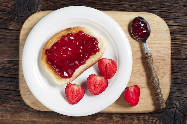 Pain grillé avec confiture et fraise sur planche à découper, vue de dessus