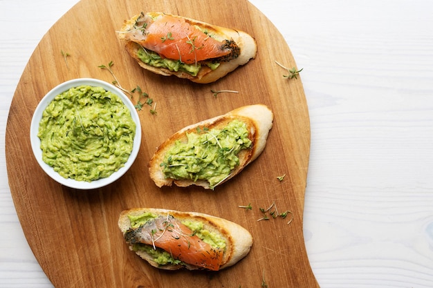 Pain grillé avec guacamole et bol de tranches de saumon à la crème d'avocat