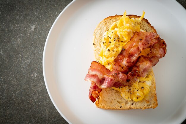 pain grillé avec oeuf brouillé et bacon sur plaque blanche