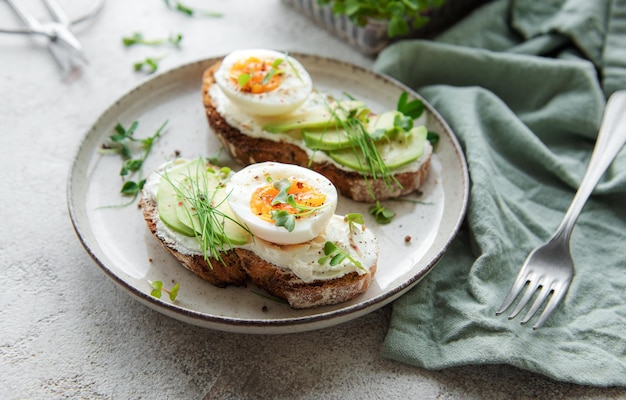 Pain grillé œufs durs tranche d'avocat microgreens sur une assiette