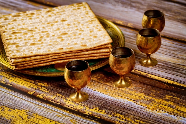 Pain juif de pâques matzoh, quatre verres de vin casher sur une table en bois.