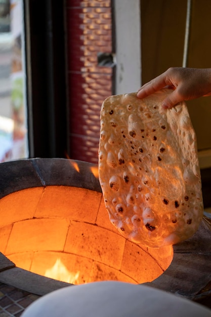 Le pain lavash cuit dans un feu de bois dans un tandoor Tandir lavas