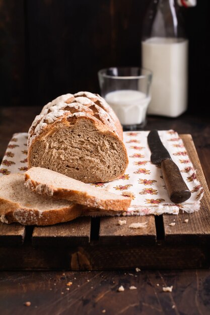 Pain maison fraîchement sorti du four avec du lait sur une vieille table en bois