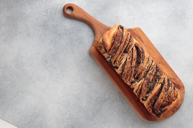 Pain maison tourbillon sucré avec des graines de pavot sur un fond de béton gris