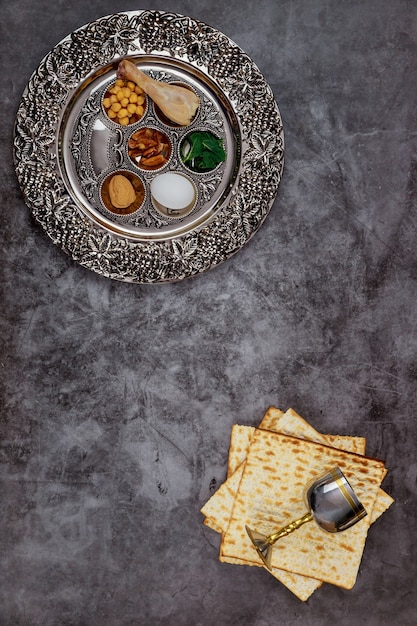 Pain de matsa juif avec coupe en argent et fleurs sur fond rustique en bois. Concept de vacances de la Pâque