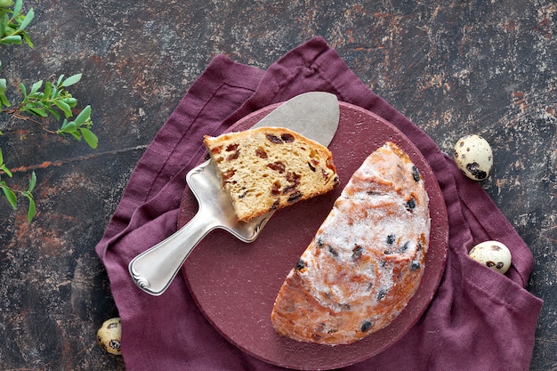 Pain de Pâques (Osterbrot en allemand). Vue de dessus du pain fruité traditionnel sur table sombre avec des feuilles fraîches et des œufs de caille