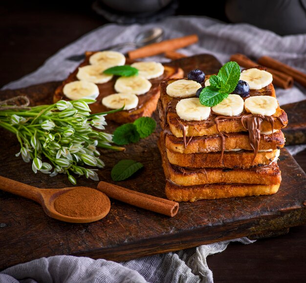 Pain perdu avec du chocolat et des tranches de banane sur une planche en bois marron