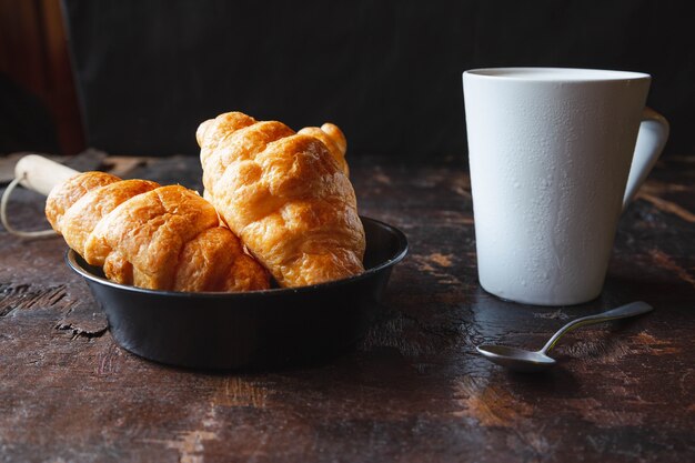 Pain de petit-déjeuner, croissants et lait frais sur la table en bois.