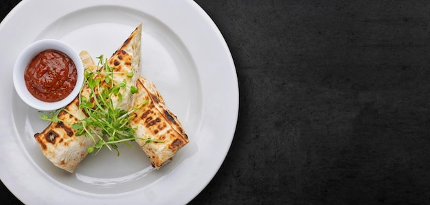 Pain pita avec sauce au fromage suluguni microgreen sur une plaque blanche sur béton gris