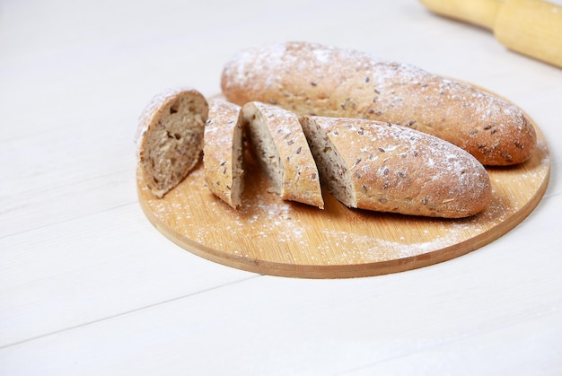 Photo pain sur une planche à découper. pain de seigle complet. sur table en bois clair