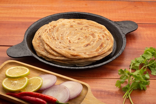 Pain plat en couches Parotta ou paratha fait maison à base de farine de blé disposé dans une poêle en fonte