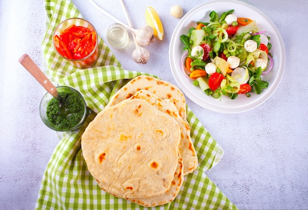 Pain plat naan indien fait maison avec salade fraîche et trempettes sur la table du dîner