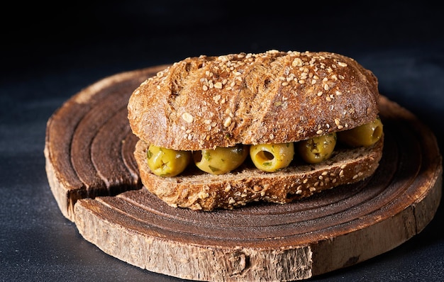 Un pain rempli de salade et d'olives sur un fond sombre
