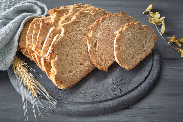 Pain rond blanc avec des épis de blé sur bois rustique gris