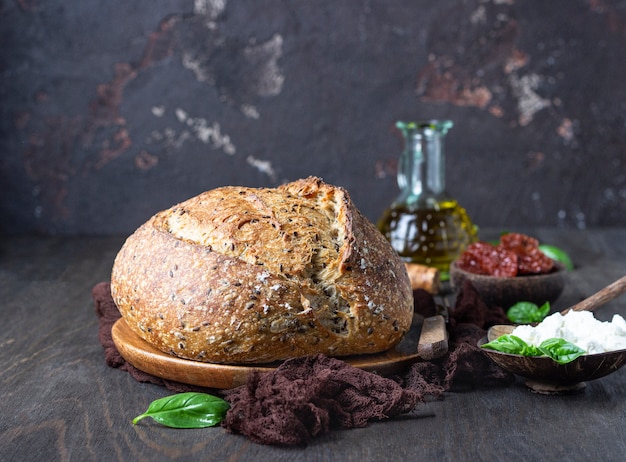 Pain rond de pain au levain fraîchement préparé avec du fromage ricotta, des tomates séchées, du basilic et de l’huile d’olive.