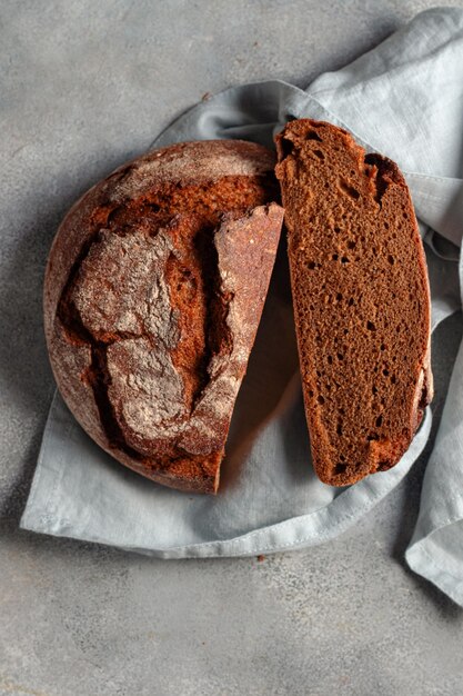 Pain sans levain tranché foncé artisanal sur fond de pierre grise avec serviette en lin bleu