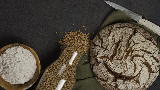 Pain sans levure de grains entiers frais sur un fond sombre entouré d'un bol en bois avec de la farine et ca