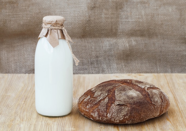 Pain de seigle avec une bouteille de lait sur une table en bois