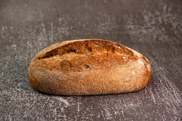 Pain de seigle complet sur une planche à découper sur une surface grise