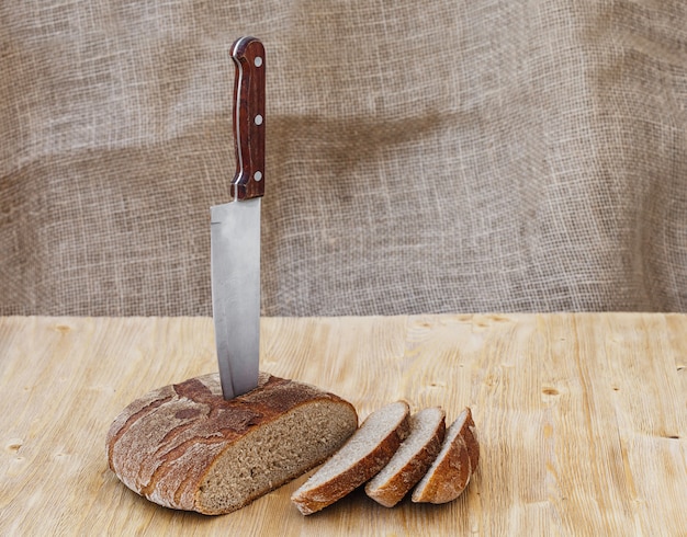 Photo pain de seigle entier frais sur une table en bois avec couteau