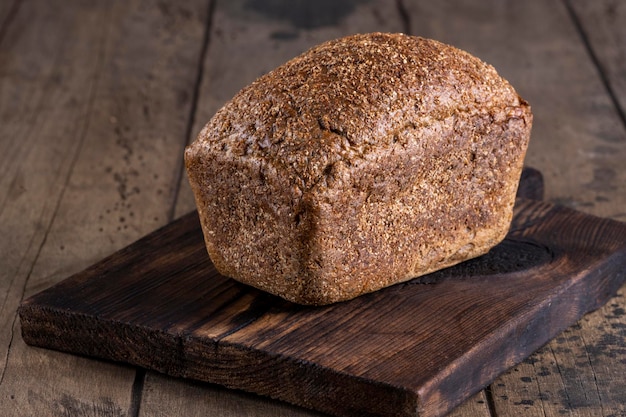 Pain de seigle fraîchement cuit sur planche de bois. Fond en bois.