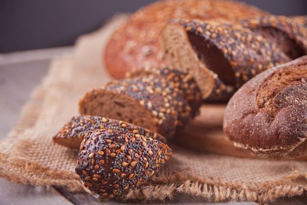 Pain de seigle fraîchement sorti du four avec céréales et graines sur la table de cuisine en bois