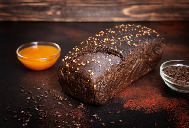 Pain de seigle à grains entiers, miel et malt sur fond de bois foncé. Pain maison fraîchement sorti du four. Gros plan, mise au point sélective