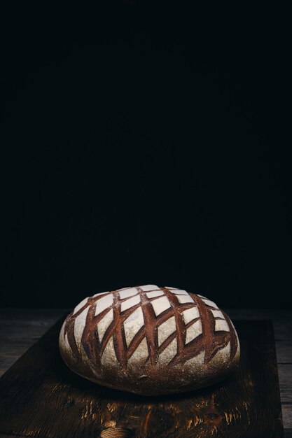 Pain de seigle noir pain saupoudré de farine sur fond sombre en bois rustique
