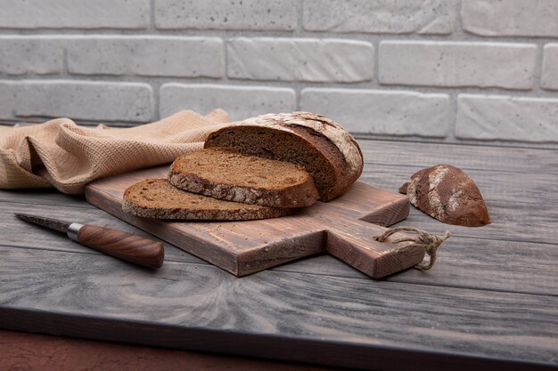 Pain de seigle pain rond coupé en morceaux sur une planche de bois avec un couteau en bois rustique.