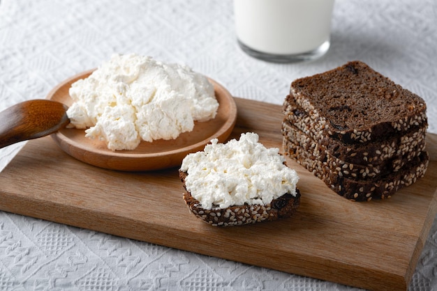 Pain de seigle sur une planche à découper en bois avec fromage blanc et lait