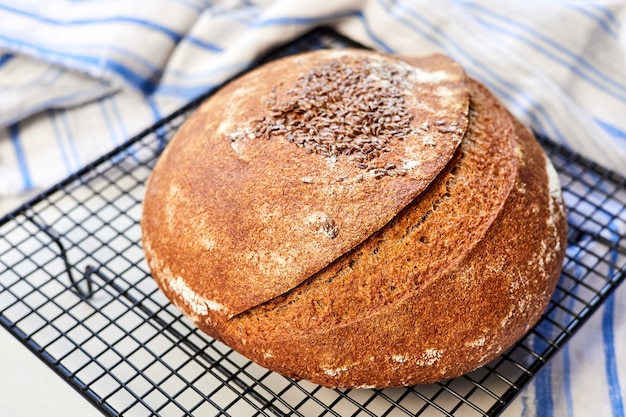 Pain de seigle rond fait maison sur une grille métallique avec un chiffon. Gros plan, mise au point sélective