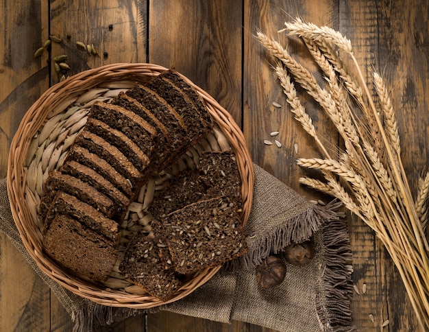 Pain de seigle tranché dans un plateau en osier et épillets sur une surface en bois