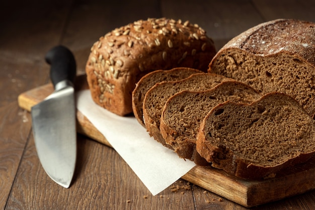 pain de seigle en tranches et un gros plan de couteau, sur une planche à découper en bois