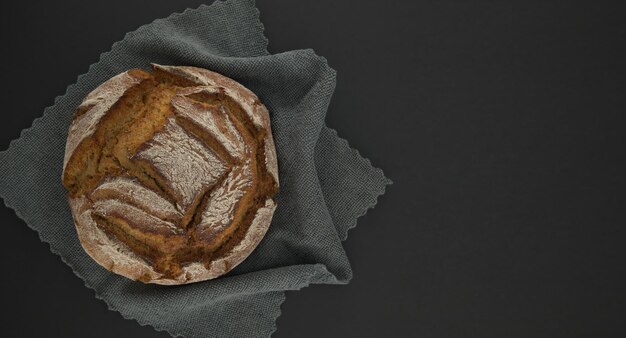 Photo pain sur une serviette de cuisine grise placée sur une table noire avec un espace de copie