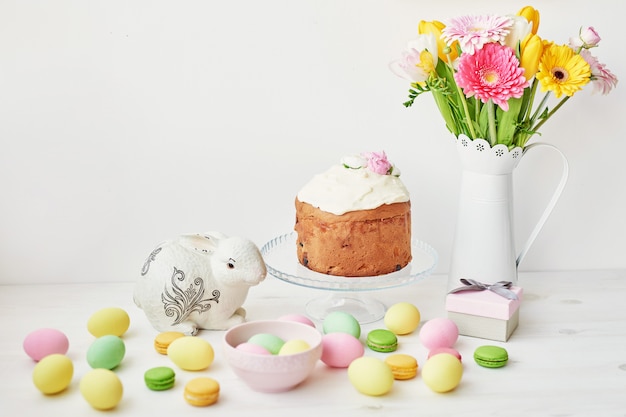 Pain sucré de Pâques, gâteau de Pâques et œufs multicolores avec tulipes et un lapin blanc. Concept de petit déjeuner de vacances avec espace copie.