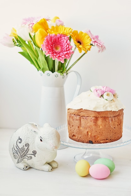 Pain sucré de Pâques, gâteau de Pâques et œufs multicolores avec tulipes et un lapin blanc.