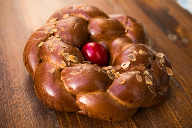 Pain sucré de Pâques traditionnel grec Tsoureki garni d'amandes effilées et décoré d'un œuf dur teint en rouge au milieu