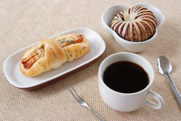 Pain de taro de saucisse appétissant et tasse de café sur un fond de tissu