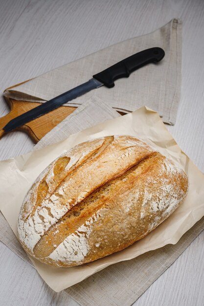 Pain tartin fraîchement sorti du four et un couteau sur une planche de bois