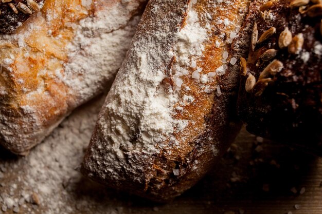 Pain traditionnel fraîchement cuit avec de la farine sur une table en bois baguette fraîche avec de la farine