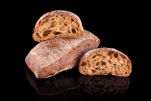 Pain tranché ciabatta italien foncé. Pain maison fraîchement sorti du four isolé sur fond noir. Une alimentation saine et une boulangerie traditionnelle, un concept de pain de cuisson.