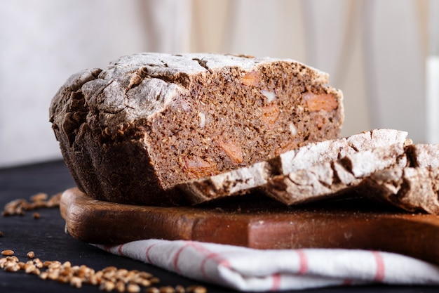 Pain tranché maison sans levure avec grains de seigle et de blé entiers sur bois noir