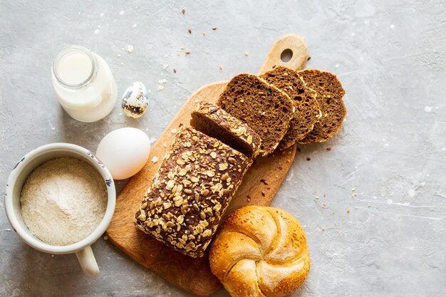 Pain tranché sur une planche avec du lait. Savoureux, beau pain fait maison avec des grains. Cuisson maison. Pâtisseries sans gluten. Pain noir avec une boîte de lait. Pain fait maison