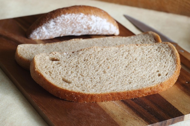 Le pain tranché se trouve sur une planche de bois Il y a un couteau à côté de lui produit de la ferme