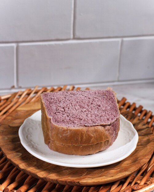 Pain violet fait maison à partir de patates douces violettes japonaises avec une couleur naturelle. Servi sur une plaque blanche sur fond blanc. Concept pour une alimentation saine Boulangerie