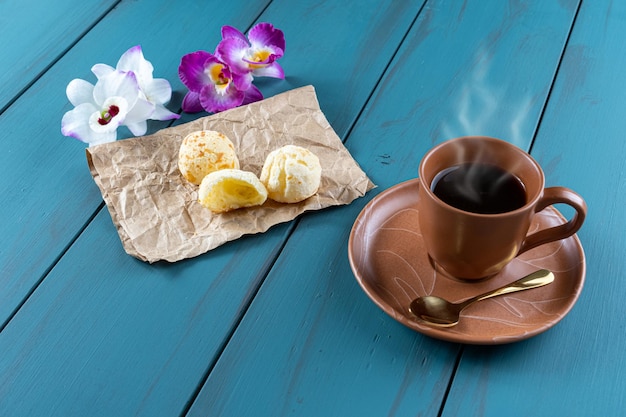 Pains au fromage brésiliens à côté d'une cuillère à café dorée et de fleurs