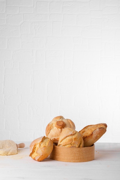 Pains de blé italiens frais dans le tamis sur la table avec de la farine et de la pâte sur fond blanc