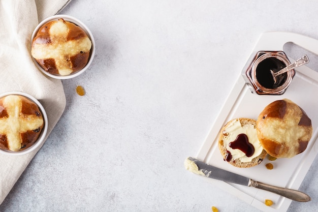 Pains croisés aux raisins secs, servis avec du beurre et de la confiture pour Pâques.