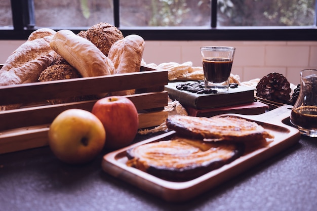 Pains cuits au four, pommes et café sur une table.